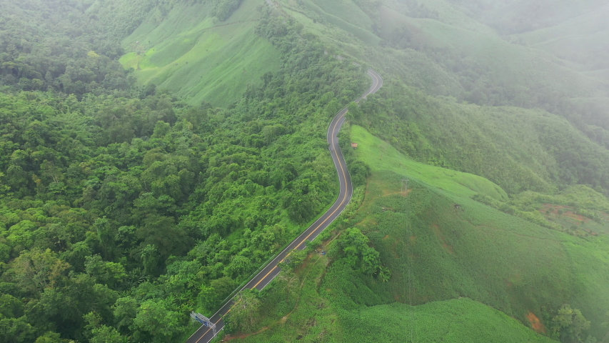 Aerial view of Beautiful sky road over top of mountains with green jungle in Nan province, Thailand. Royalty-Free Stock Footage #1057588792