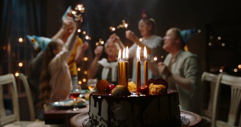 Large happy family celebrating birthday. Cheerful family members of different generations holding sparklers and smiling with birthday cake in front - real people, celebration concept 4k footage