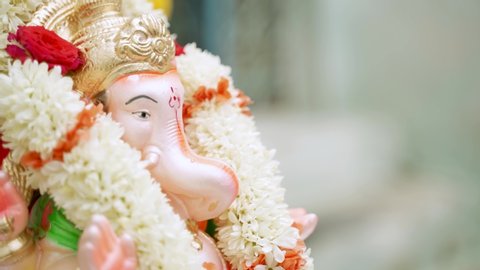 Closeup of hands applying Tilak or Kumkum to Lord Ganesha during Indian religious ganesha or vinayaka Chaturthi festival ceremony.