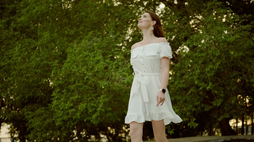 Young charming woman walking in a summer park at sunset