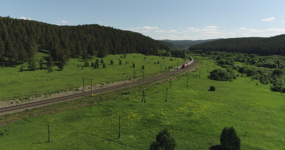 Passenger train an electric locomotive by two-sided winding Trans Siberian railway in the Ural Mountains - Aerial Photography, drone wide view at summer sunny day Royalty-Free Stock Footage #1057594990