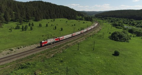 Passenger train an electric locomotive by two-sided winding Trans Siberian railway in the Ural Mountains - Aerial Photography, drone wide view at summer sunny day