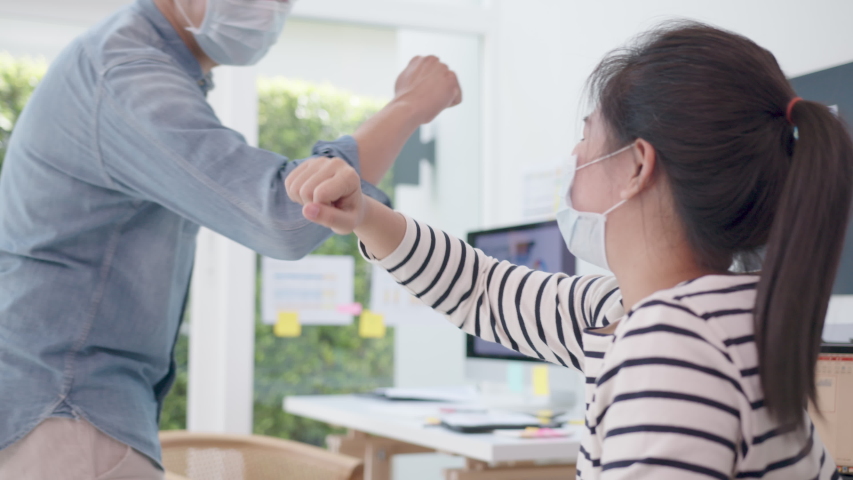 Elbow greeting to avoid the spread of coronavirus (COVID-19). Asian officer man and woamn wear face mask greeting with elbow bump at new normal office. Employee avoid touch for coronavirus prevention Royalty-Free Stock Footage #1057595440