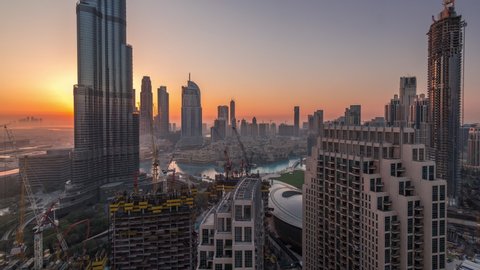 Panoramic skyline view of Dubai downtown before sunrise with mall, fountains and tallest tower aerial night to day transition timelapse. Modern skyscrapers and construction site