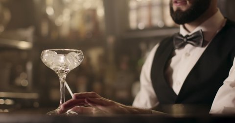 Close-up shooting. Bartender is turning the ice in glass using the bar spoon. 4k