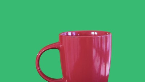 Close up shot of red tea mug and disposable tea bag taken into boiling water, tea bag is slowly put in and out of the cup.Studio shot on green background.Relaxing,food, tea break concept.