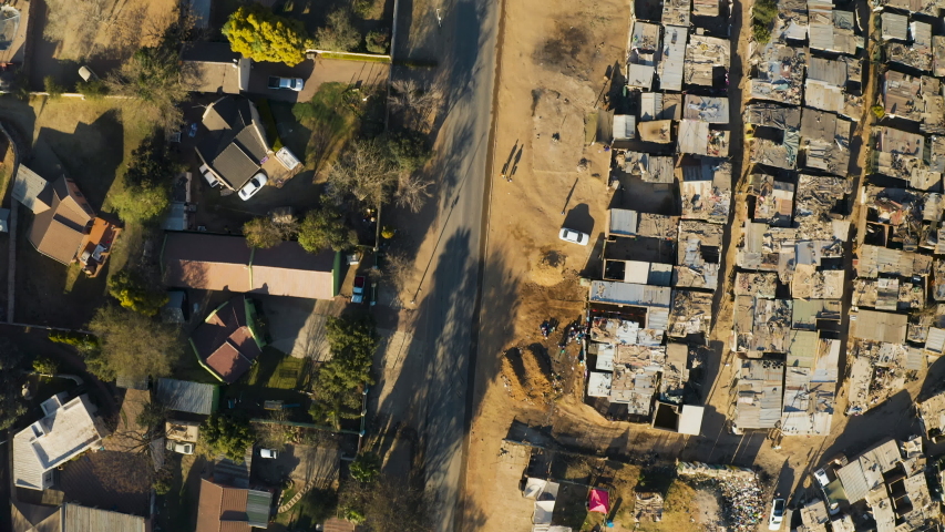 Poverty.Inequality.Aerial close-up straight down view of an informal settlement Kya Sands squatter camp right next to middle class suburban housing, Gauteng Province, South Africa | Shutterstock HD Video #1057610035