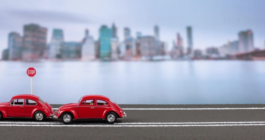 Chisinau 10.08.2020:Video of an accident between two new red car figurines, before a stop sign on the highway, with a blurred city image in the background. | Shutterstock HD Video #1057610338
