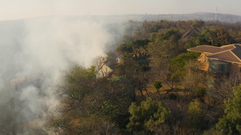 Climate emergency.Aerial close-up view of a grass fire burning very close to a housing estate in Southern Africa. Fire is caused by drought and climate change