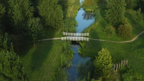 Aerial view of a pretty bridge crossing a river on a nature trail within woodlands in Holland.