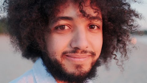 Handsome Bearded Latin American or Arab Man Looking in Camera. Confident and Successful Male Person Posing on Camera Outdoors. Authentic Appearance, Curly Hair, Super Close-up.