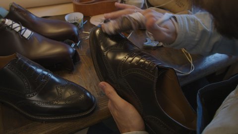 Close up shoe manufacturing workshop. Shoemaker rubs shoes with cream sews shoes. Handmade work shoes. Leather shoes. 