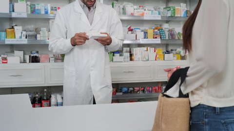 Customer making payment using credit card with swipe through terminal  in modern pharmacy. Thai text translations Eye medicine, Gastrointestinal drugs, Respiratory medicine, Muscle relaxants
