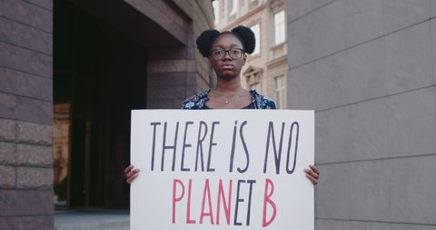 Young african american woman holding there is no planet b cardboard while standing at city street. Female activist supporting eco campaign. Concept of environmental protection. Zoom in.