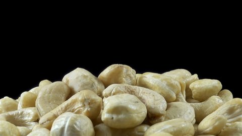 Heap of cashew nuts on a plate on a black background. Close-up