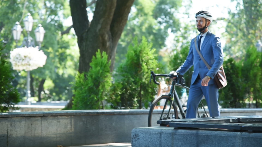 Young Bearded Businessman Riding A Bicycle To Work. Business, Lifestyle, Transport And People Concept. Slow Motion Effect.