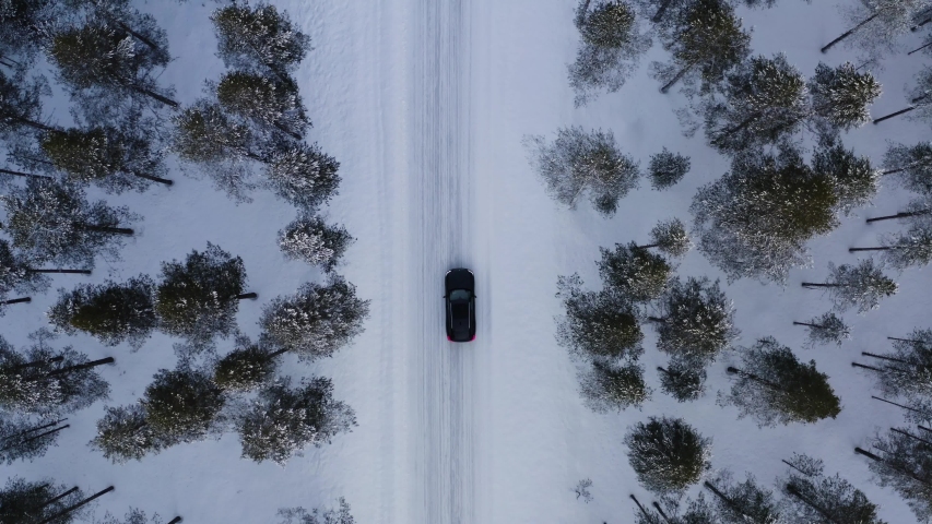 Aerial top view from drone of suv vehicle driving on snowy ice road exploring local landscapes in winter, bird’s eye view of automobile car moving on area surrounded by beautiful coniferous forest
 Royalty-Free Stock Footage #1057628311
