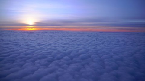 Flying on an airplane. Sunrise or sunset from an airplane illuminator. An airplane wing flies through cotton clouds. The view from the window of the plane. Airplane. Travel by air. Colorful sky