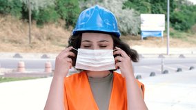 Young female engineer or worker in protective blue helmet wearing face mask prevent from covid-19 pandemic virus at construction site. Healthy lifestyles  4k Resolution, slow motion. - Powered by Shutterstock - Get 15% off with code: PIKWIZARD15