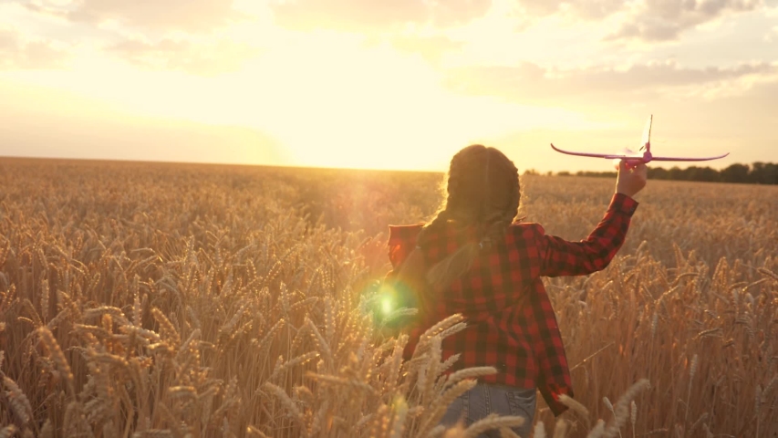Little happy girl runs with a toy airplane across the field in the park. A young girl plays with a toy plane and dreams. The girl wants to become a pilot and an astronaut. Dreamer airplane pilot | Shutterstock HD Video #1057631941