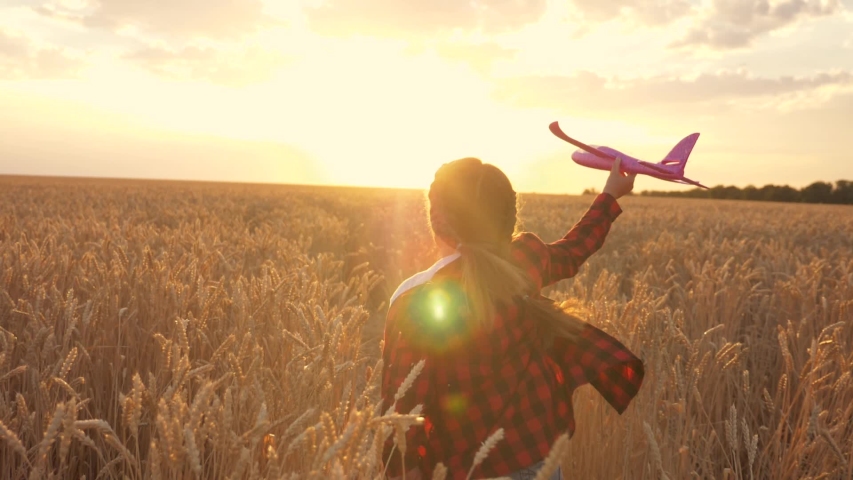 Little happy girl runs with a toy airplane across the field in the park. A young girl plays with a toy plane and dreams. The girl wants to become a pilot and an astronaut. Dreamer airplane pilot | Shutterstock HD Video #1057631941
