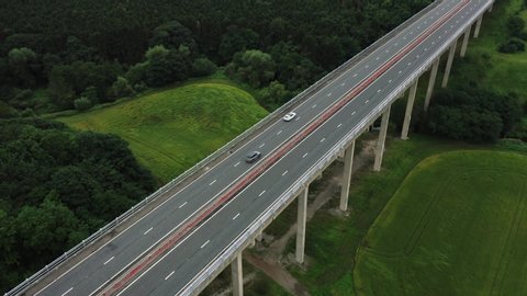 Aerial drone footage flying around a large viaduct which supports a dual carriageway motorway that spans over a luscious green valley in the North East of England, UK