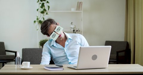 Tired comic male man manager pretends working sleeping with stickers on face sitting at desk laptop. Funny lazy office businessman student napping at workplace covering eyes with sticky notes glasses