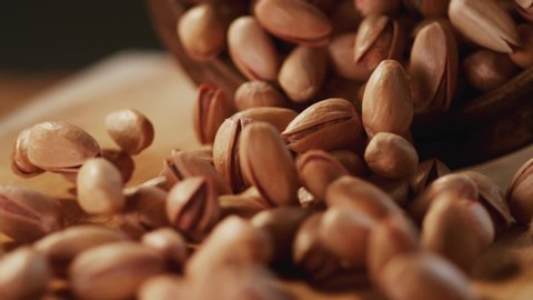 Macro,Phantom Camera,Very Close-up, 900 fps video.In a beautiful light, pistachios fall into the wooden plate in slow motion. 