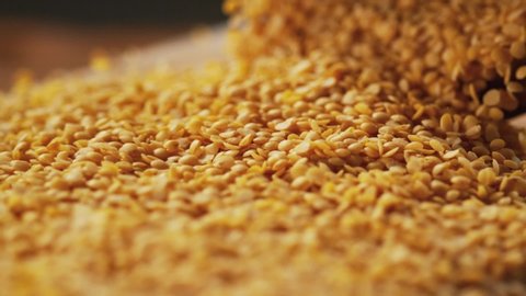 Very Close-up, 900 fps video.Yellow lentil grains on a delicious background and wood floor passes in front of the camera in slow motion. Macro,Phantom Camera.