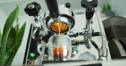 CINEMAGRAPH SEAMLESS LOOP VIDEO: Coffee espresso machine perfect extraction pouring from bottomless naked portafilter. Coffee equipment at home or cafe shop. Closeup of brown slow motion.