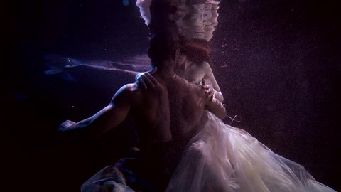 sexy man and woman are floating underwater and embracing, sensual subaquatic shot