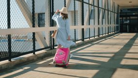 Slow motion of woman in protecting face mask. Young attractive woman walking between airport terminals with pink travel bag on sunny day. Safety travels under the COVID-19 restrictions. Coronavirus - Powered by Shutterstock - Get 15% off with code: PIKWIZARD15