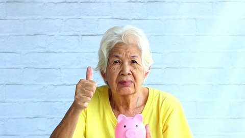 Senior women Show piggy bank drops and thumbs up business concepts ideas of investment retirement finance and save money for future.