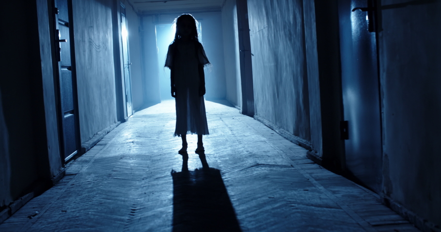 The little girl in white dress looking like a ghost carelessly the hallway of a haunted house. Halloween costume party, horror movie 4k footage | Shutterstock HD Video #1057653184