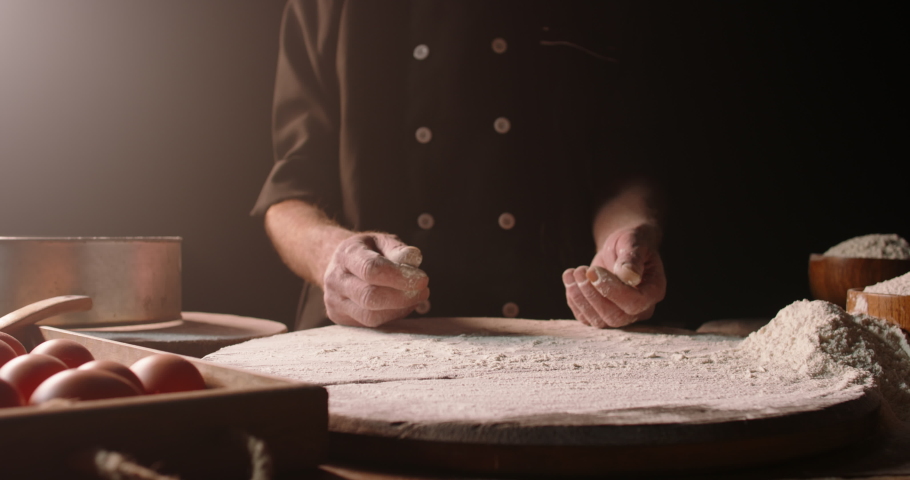 Experienced professional chef getting rid of flour on his hands, starting to make pizza or bread dough at bakery, isolated on black background close up 4k footage Royalty-Free Stock Footage #1057653241