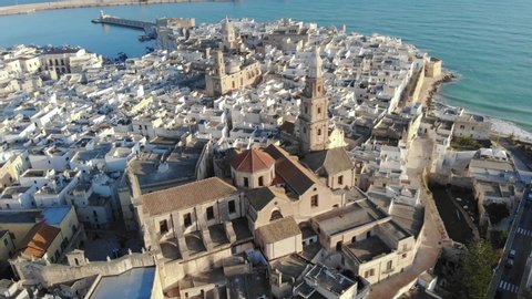 Aerial shot of a beautiful italian city by the sea. Drone flight over old town of Monopoli. View of the sea, houses and churches. Bari, Puglia, Italy. 4K