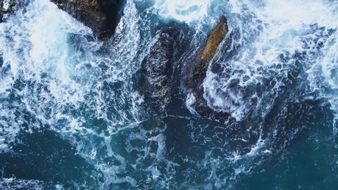 Top view of big sea waves crashing at rocks at the sea coast