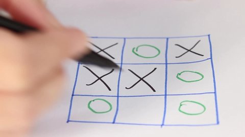 Two people are playing TIC-TAC-toe on paper. Close-up, selective shot.