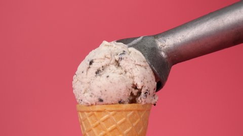 Ice cream Cookies & Cream scoop in waffle cone on pink background, Front view Food concept.