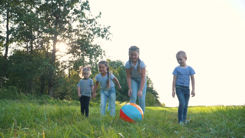 Happy family of children playing with a ball in park. Happy kid are run. Children run after ball in  park. Happy family of children at sunset in park, having fun playing with a ball. Kid dream team. Royalty-Free Stock Footage #1057662967