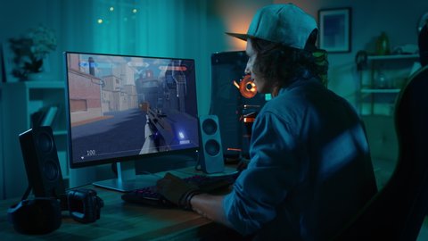 Professional eSports Gamer Plays 3D Shooter Mock-up Video Game with Lots of Action and Fun on His Powerful Personal Computer. Cyber Gaming Stylish Retro Neon Room