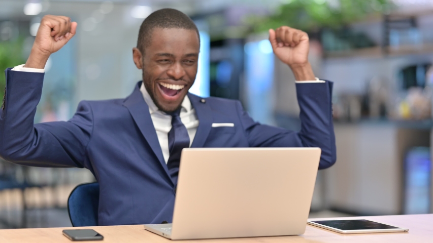 Excited African Businessman Celebrating Success on Laptop in Office  | Shutterstock HD Video #1057675987