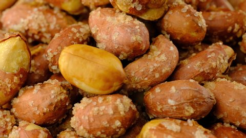 Peanuts macro background texture. Roasted salty nuts closeup rotating.