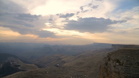 Sunset time-lapse from a high cliff next to a cliff. View of the valley with serpentine mountain roads and mountains