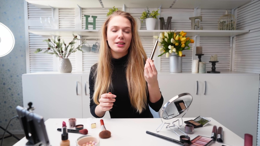 Beauty blogger woman filming daily makeup routine tutorial on camera. Influencer blonde lady live streaming eyelashes mascasra review in home studio with professional lighting equipment. Vlogger job. | Shutterstock HD Video #1057687891