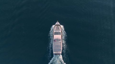 Powerboat floats on the blue water of the lake, aerial view slow motion. A large vessel with group of tourists goes on vacation on a rented boat. This is a very popular type of recreation.