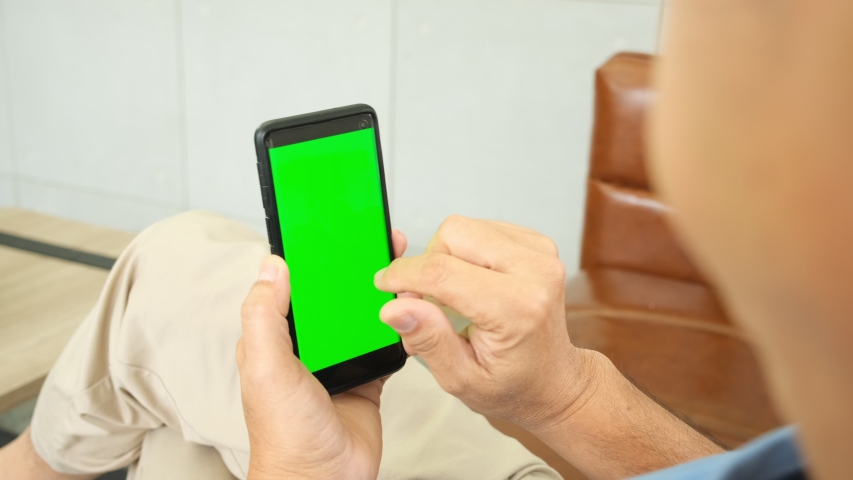 Back view of asian senior man holding and using smartphone with chroma key green screen.Lifestyle of people reading message and content technology at home,copy space with vertical vdo. | Shutterstock HD Video #1057697371