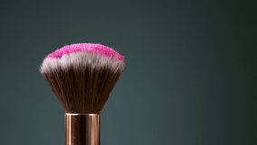 Makeup brushes touch each other on dark background and small particles of cosmetics, super slow motion, 1000 fps.