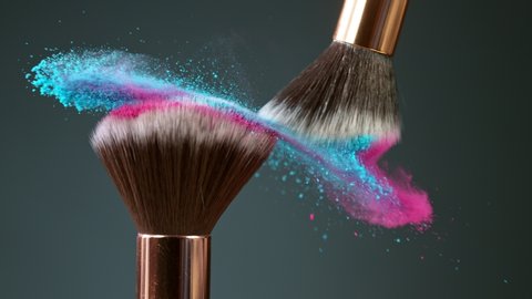 Makeup brushes touch each other on dark background and small particles of cosmetics, super slow motion, 1000 fps.