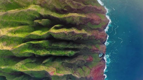 Cinematic Hawaii nature landscapes. Scenic Na Pali coast with beautiful ridges of volcanic mountains. Incredible scenery of green and red weird-shaped peaks over the deep blue ocean. Bird eye outdoors